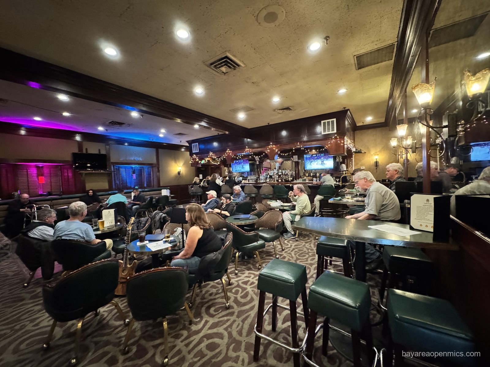 The bar at Three Flames Restaurant in San Jose, with green leather chairs and dark wood