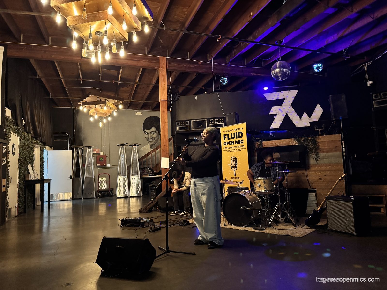 A performer backed by the house band late in the Fluid open mic