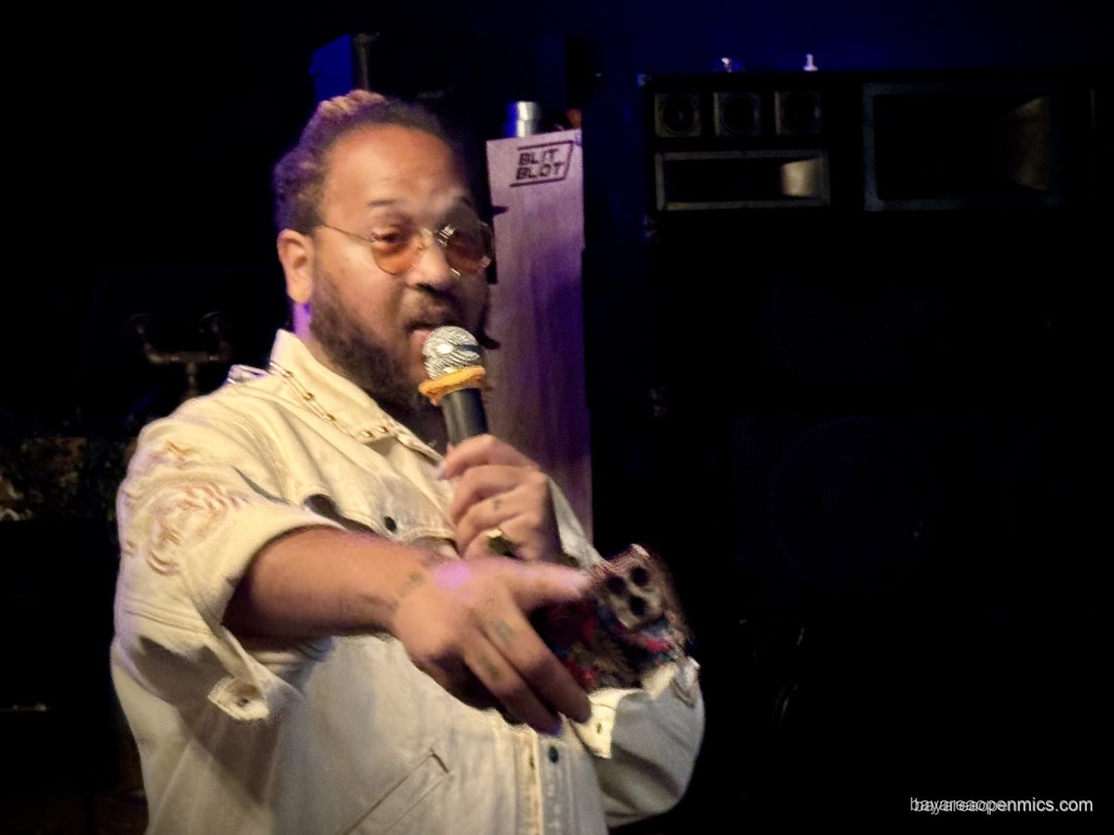 Muzik Ra gestures while being introduced onstage at the Fluid open mic