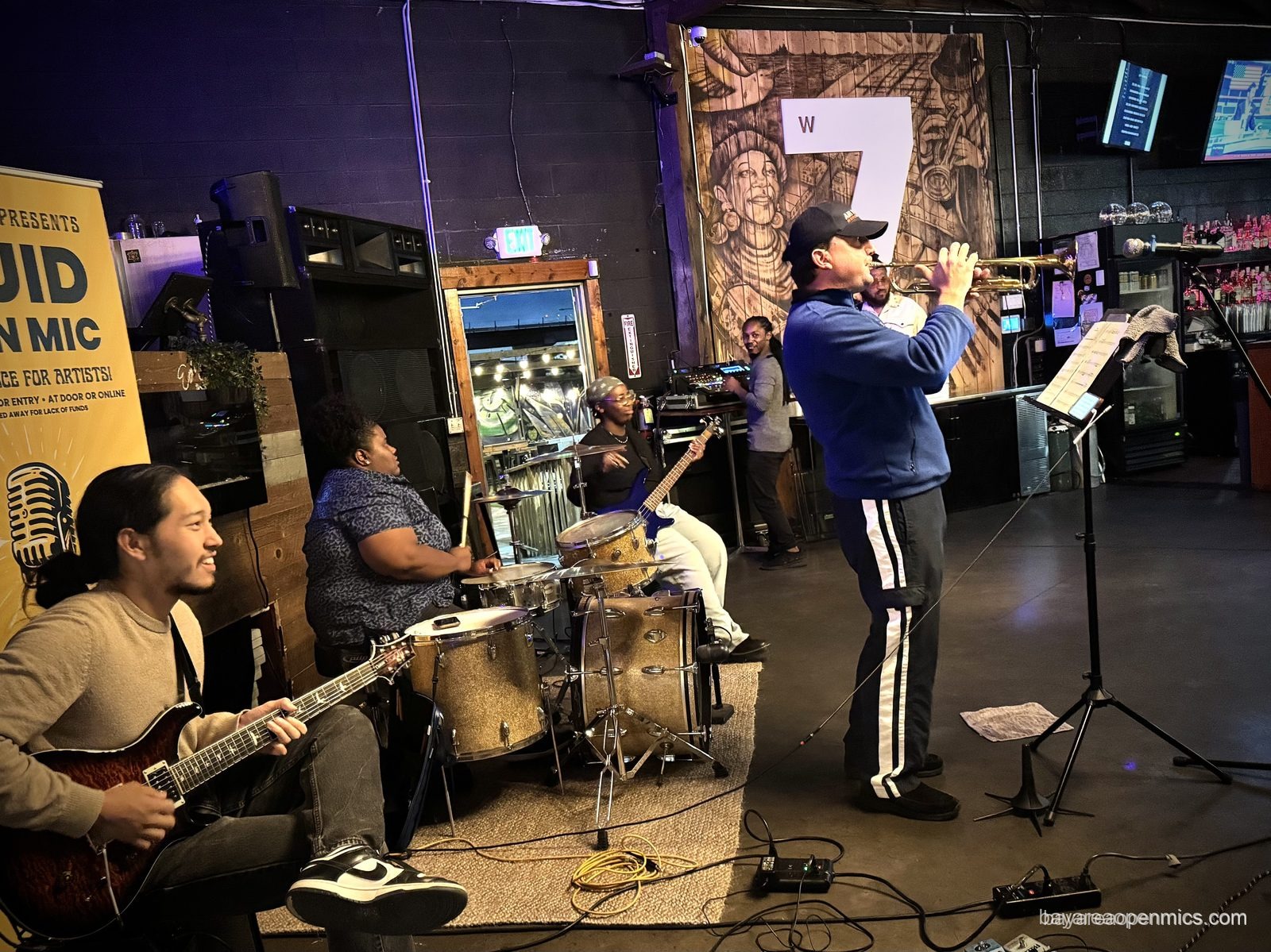 A trumpet player performs with the house band at the Fluid open mic