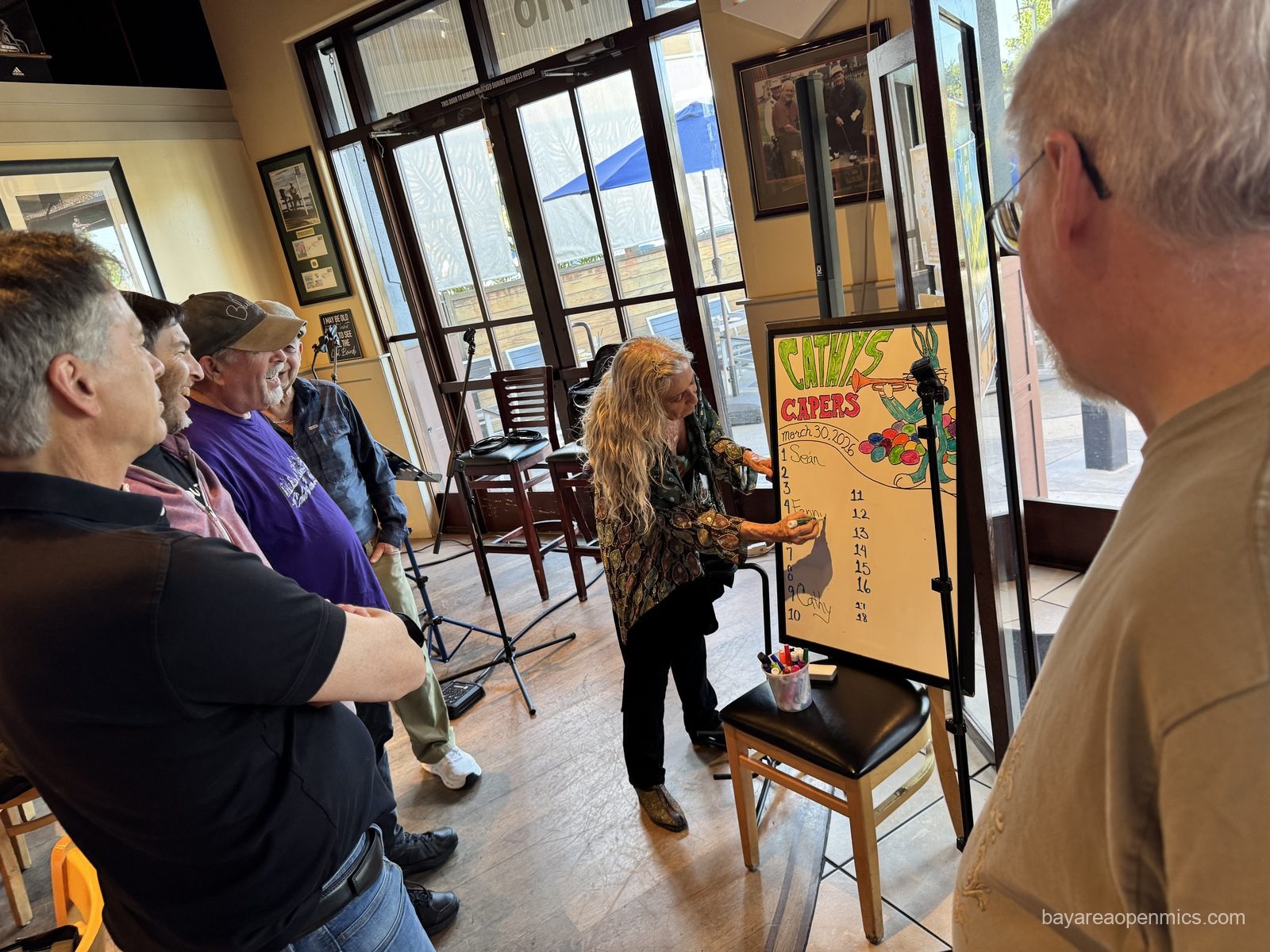 a crowd of people stand around a white board sign up list