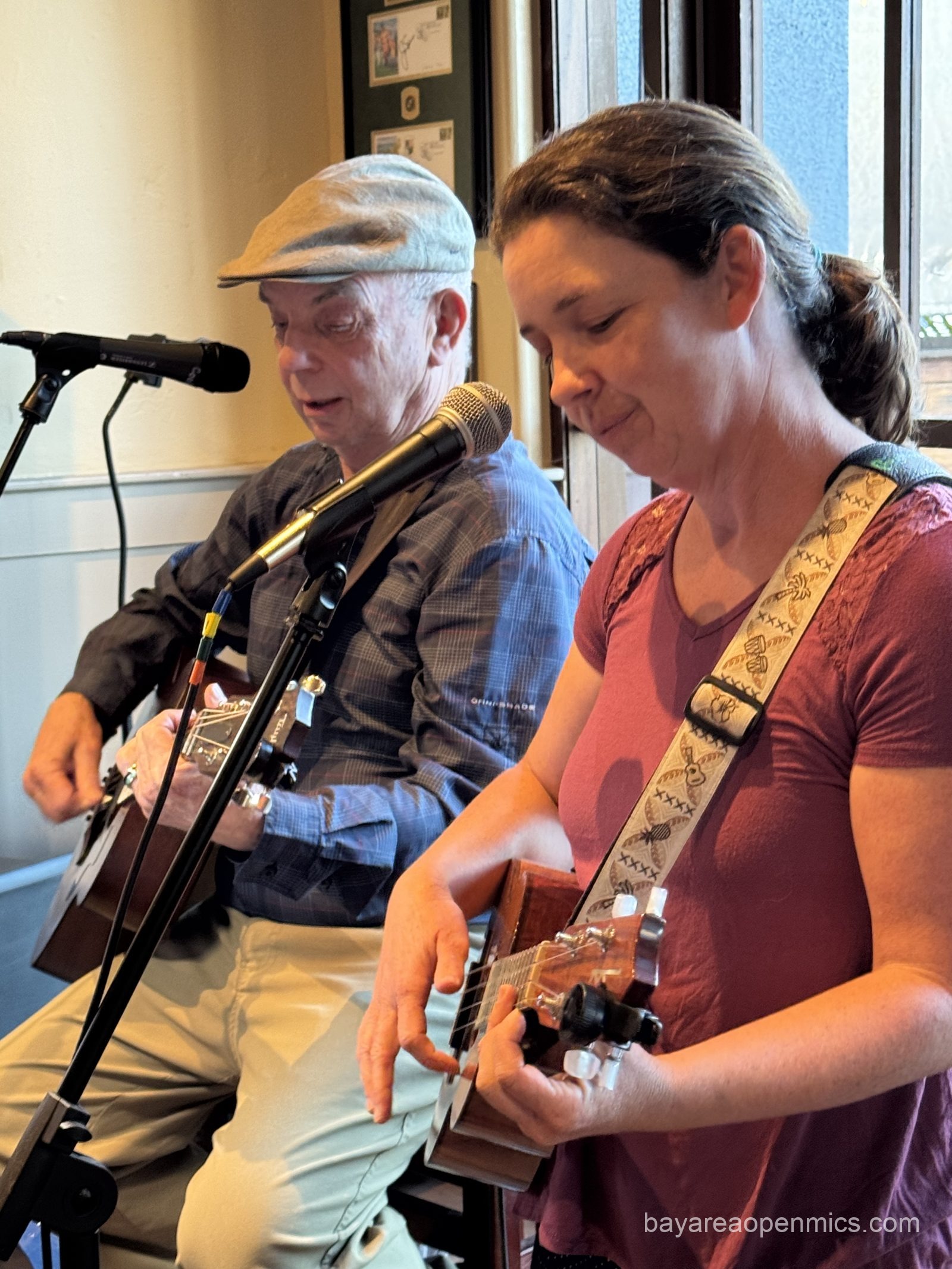 a young woman plays ukulele accompanied by an older man on guitar