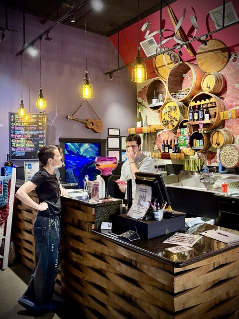 The bar at Pinot's Palette in Livermore, with wine bottles on shelves and a row of bar stools