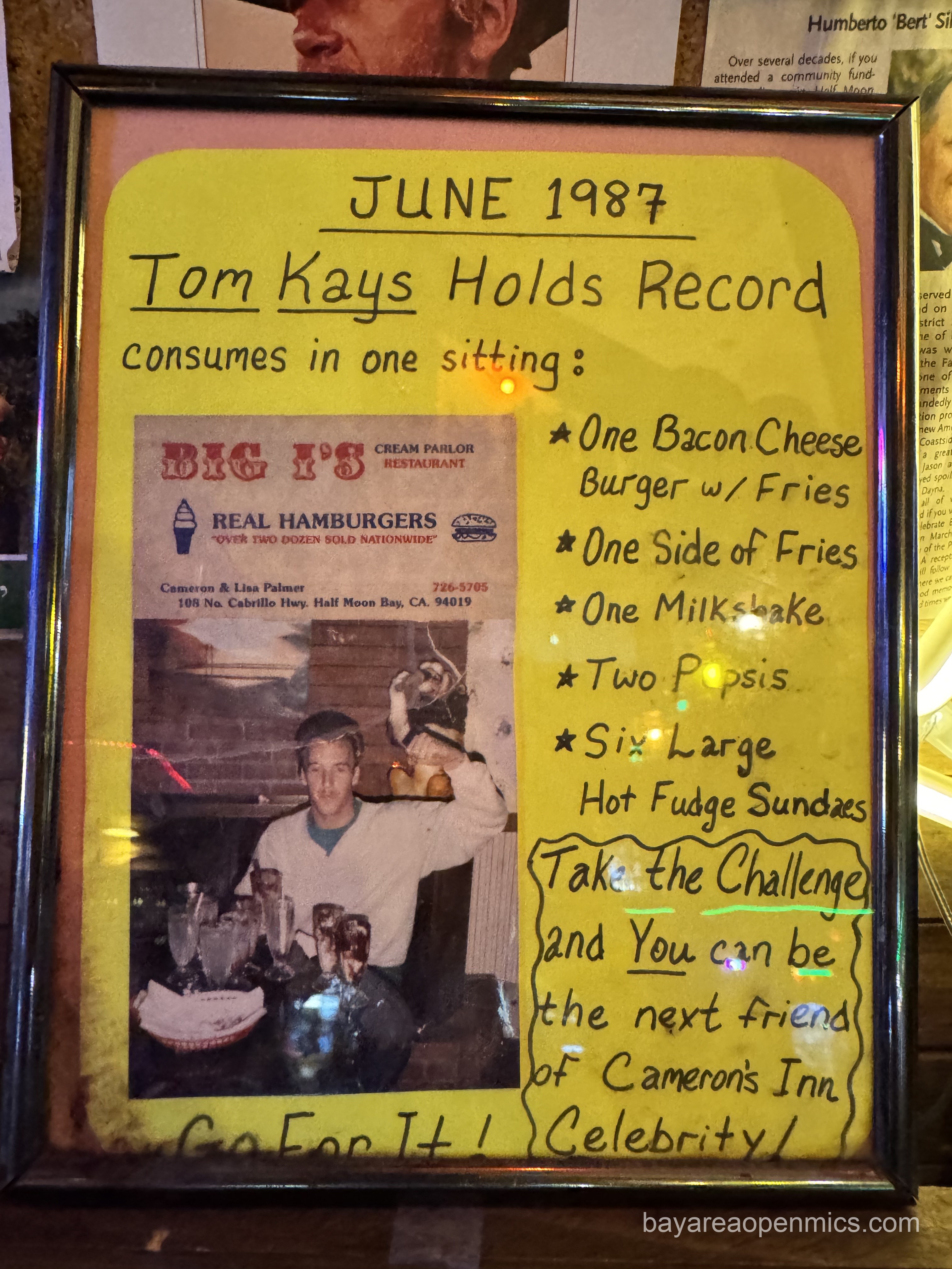 A sign declaring Tom Kays holds the eating record since June 1987 for eating One Bacon Cheese burger w/ Fries, One Side of Fries, One Milkshake, Two Pepsis, and Six Large Hot Fudge Sundaes