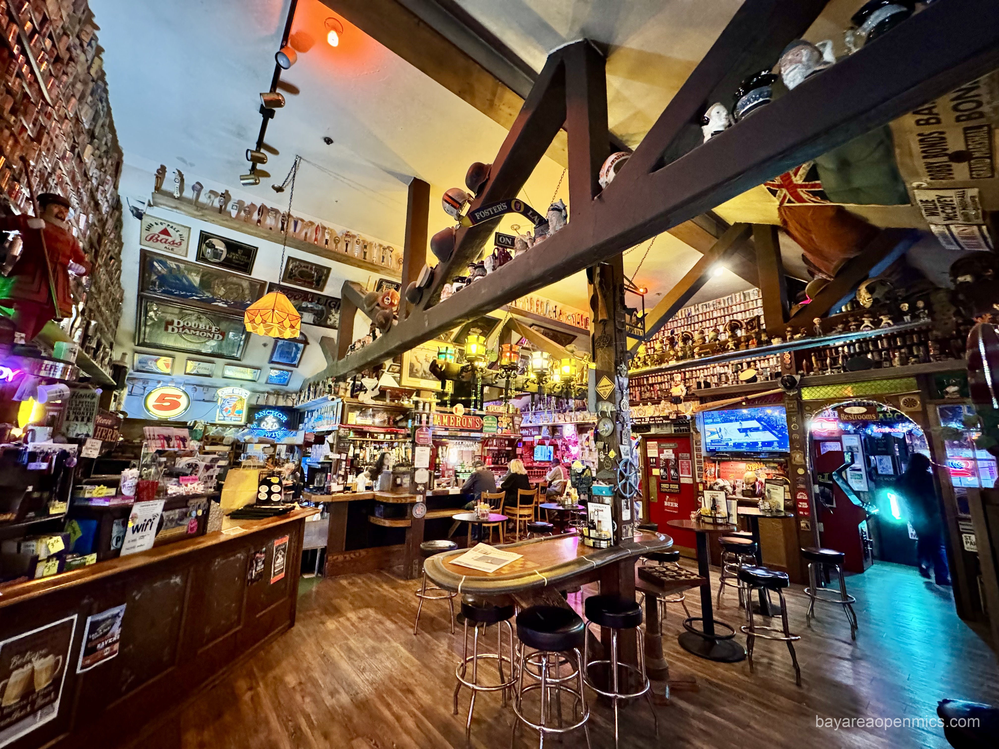 A fabulously eclectic and cluttered bar room with high ceilings and exposed wooden beams